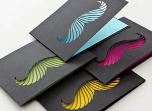 black cards with coloured moustache cut outs
